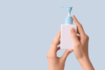 Female hands with bottle of natural cream against color background, closeup