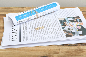 Newspapers and word NEWS made of cubes on wooden table