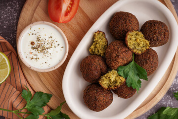 Plate with delicious falafel balls and sauce on grunge background, closeup