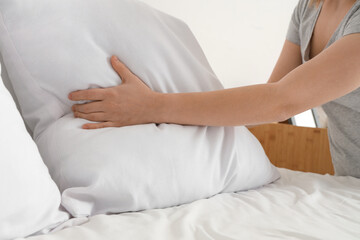 Woman making bed in modern bedroom, closeup