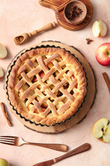 Tasty homemade apple pie with fruits, cinnamon and cutlery on beige grunge background