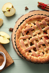 Tray with tasty homemade apple pie, fruits and cinnamon on green wooden background
