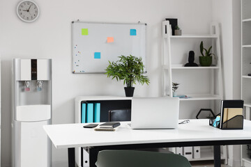 Interior of light office with modern water cooler near white wall