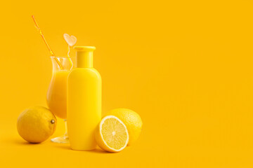 Bottle of sunscreen cream, glass of juice and lemons on color background
