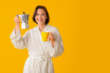 Beautiful young happy woman in bathrobe with cezve and cup of coffee on yellow background
