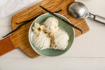 Bowl of sweet vanilla ice-cream balls with sticks and flower on white wooden background