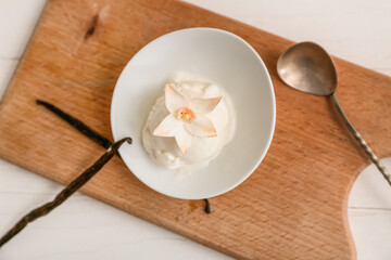 Bowl of sweet vanilla ice-cream ball with flower and sticks on white wooden table