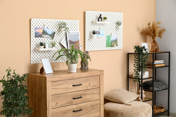 Beautiful living room with cozy pouf, chest of drawers, shelving unit and pegboard