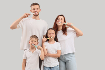 Happy family brushing teeth on light background