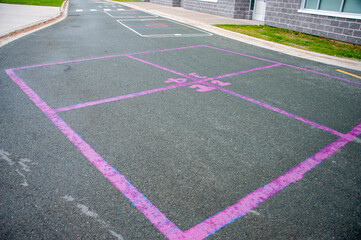 Leisure and creative childhood game of four squares. The colourful squares are outlined using pink caulk and the numbers are pink in color. The outdoor children's game is on black asphalt pavement.