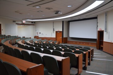 college classroom featuring vacant seats and a projector screen.