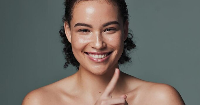 Woman, face and shush in studio for acne, finger and secret for pimple treatment on gray background. Female person, portrait and mystery for cosmetics, emoji and privacy for breakout drama on lip