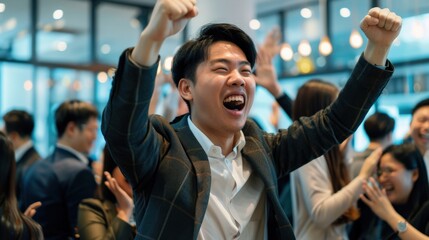 A man in a suit is smiling and holding his hands up in the air. He is surrounded by a group of people who are also smiling and looking at him. Scene is happy and celebratory