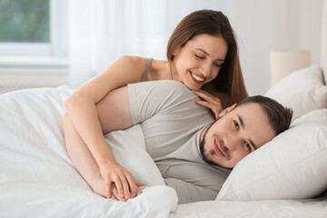 Happy couple enjoying each other in bed at home