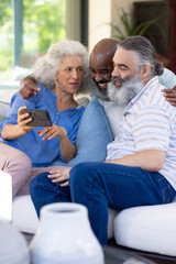 At home, Group of senior friends looking at smartphone together, sitting on couch