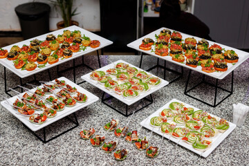 Sandwiches, canapes and vegetable snacks on white plates during buffet breakfast at the hotel.