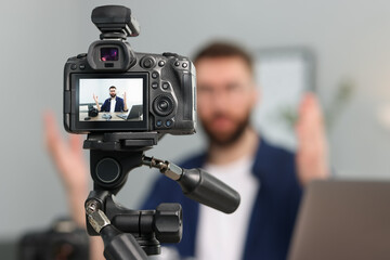 Technology blogger explaining something while recording video at home, focus on camera