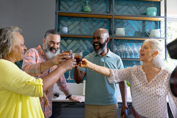 At home, Group of friends toasting with drinks in kitchen, enjoying time together