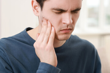 Sad man suffering from toothache at home