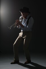 Fototapeta premium Professional musician playing trumpet on dark background
