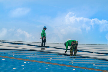 Worker Technicians are working to construct solar panels system on roof. Installing solar photovoltaic panel system. Men technicians walking on roof structure to check photovoltaic solar modules.