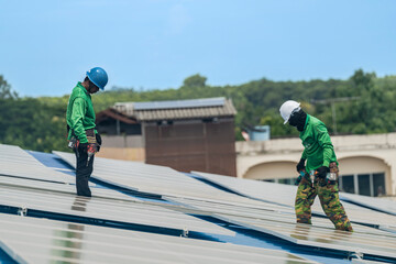 Worker Technicians are working to construct solar panels system on roof. Installing solar photovoltaic panel system. Men technicians walking on roof structure to check photovoltaic solar modules.