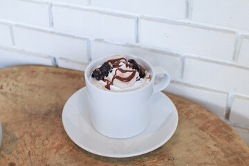 Hot chocolate served with whipped cream in white cup on wooden table.  Christmas and New Year sweet drink and food holiday concept
