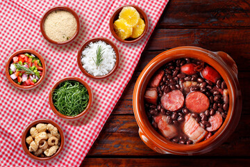 Brazilian feijoada, traditional food from Brazil cuisine, on ceramic casserole bowl, over rustic wooden table