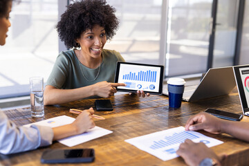 Businesswoman presenting data on tablet during casual meeting with colleagues