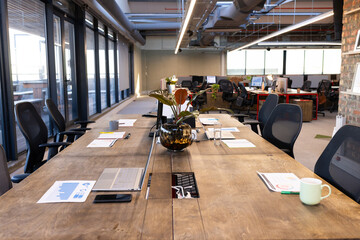 Modern office with laptops and documents on large wooden table, ready for meeting
