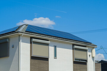 青空とソーラーパネルを設置した住宅　エコ　再生可能エネルギー