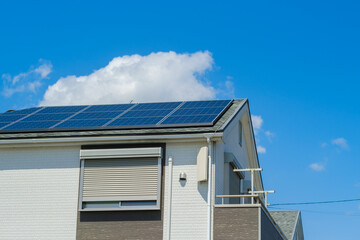 青空とソーラーパネルを設置した住宅　エコ　再生可能エネルギー