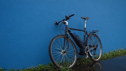 Fototapeta premium bike is parked in front of a blue wall and a small stream of water