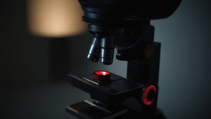 close up of a microscope with a light on the top of it and a red button on the bottom