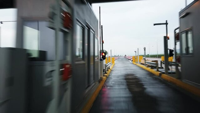 Car pov drive passing the highway pay toll booths with automatic card readers and lines divided with traffic cones