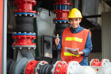 Asian engineer diligently inspects machinery in an industrial factory.Asian workers diligently...