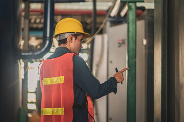 Asian engineer diligently inspects machinery in an industrial factory.Asian workers diligently...