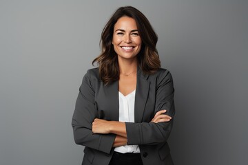 Portrait of a happy business woman with arms crossed over grey background