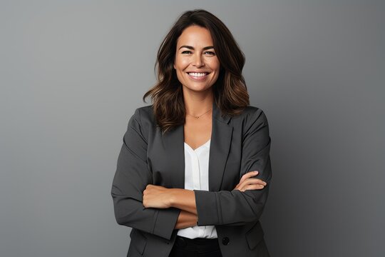 Portrait of a happy business woman with arms crossed over grey background