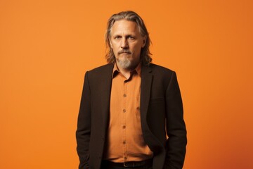 Fototapeta premium Portrait of handsome mature man with grey hair and beard in orange shirt.