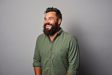 Obraz premium Portrait of a happy bearded man in a green shirt on a gray background