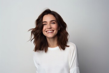 Obraz premium Portrait of beautiful young woman looking at camera and smiling while standing against grey background