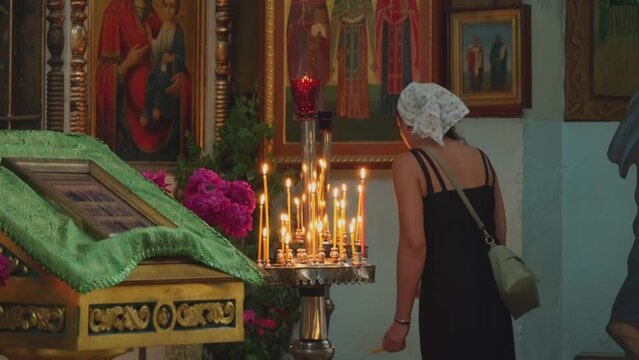 A believing woman in an Orthodox church prays in front of holy icons. The concept of religion, hope and faith. The Church of the Ascension of the Lord.
