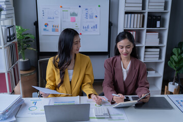A professional photograph depicting two female entrepreneurs engaged in a collaborative discussion while diligently working in their corporate office environment.