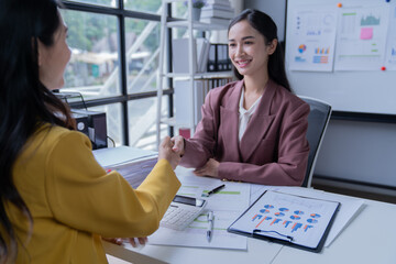 A professional photograph depicting two female entrepreneurs engaged in a collaborative discussion while diligently working in their corporate office environment.