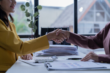 A professional photograph depicting two female entrepreneurs engaged in a collaborative discussion while diligently working in their corporate office environment.