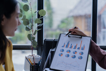 A professional photograph depicting two female entrepreneurs engaged in a collaborative discussion while diligently working in their corporate office environment.