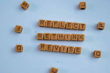 Concept of Reflect, Rethink, Revise written on wooden blocks. Cross processed image on Wooden Background
