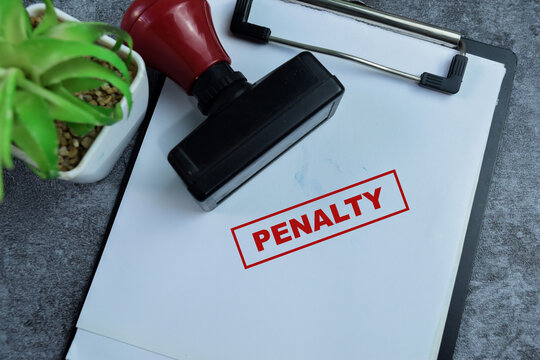 Red Handle Rubber Stamper and Penalty text above paperwork isolated on wooden background
