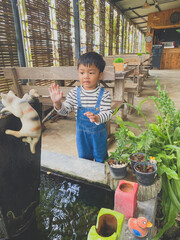 Hispanic child enjoying gardening outdoors with potted plants and watering them in the summer